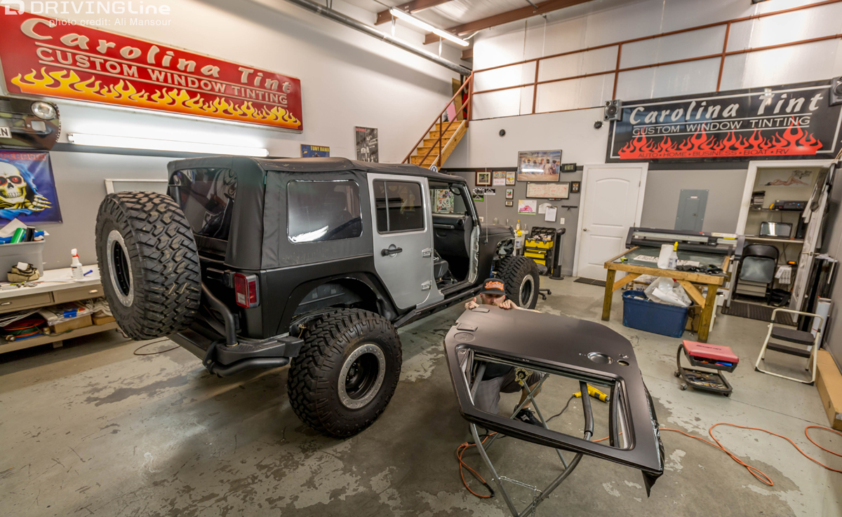 Jeep Wrangler in a shop with its door off and 3M 1080 Satin Black vehicle wrap on it