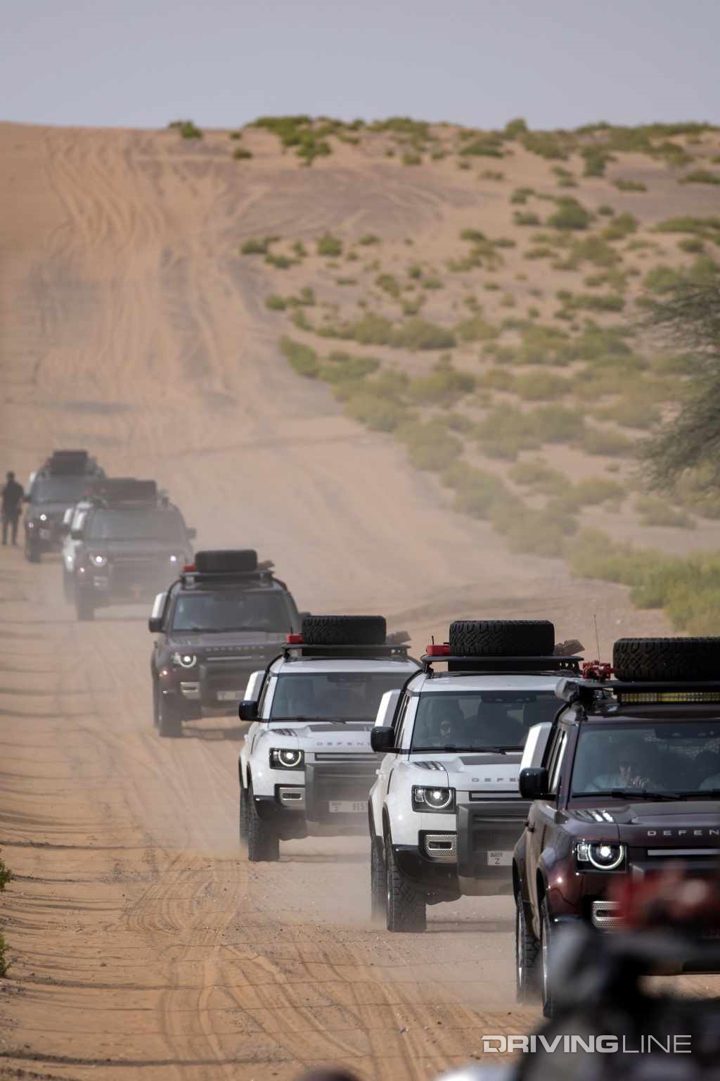 Land Rover Defender 110 in a line on desert road